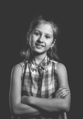 Siyah arka planda poz veren sevimli küçük bir kız. Tek renkli fotoğraf..