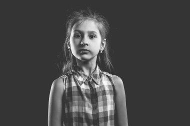 Siyah arka planda poz veren sevimli küçük bir kız. Tek renkli fotoğraf..