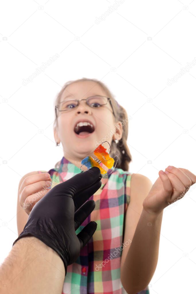 The reaction of a little girl to the proposal to wear an orthodontic appliance. Studio photo isolated on white background.
