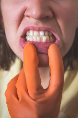 Eldivenli kadın çarpık dişlerini gösteriyor.