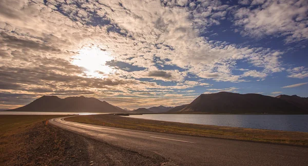 Hermoso puente de carretera vacío que conduce a la montaña con colorido paisaje nublado en Islandia —  Fotos de Stock