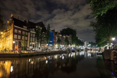 Hollanda'nın Amsterdam, su yansıması ile kanal boyunca geceleri güzel geleneksel eski binalar