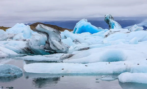 Jokulsarlon, buzul nehir lagün, büyük buzul Gölü, Güneydoğu İzlanda, kış gün görünümü, Vatnajkull Milli Parkı, İzlanda'nın doğa harikalarından biri kenarında çarpıcı. Büyük parlak mavi buzdağı hayalet at binme At benzer