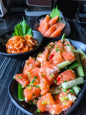 Somon balığı (taze Çiğ somon et) ile Japon yemekleri somon tataki (baharatlı somon salata) ve kimuchi (kimchi soslu baharatlı haşlanmış tarak) bir arka plan olarak hotate