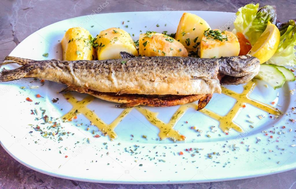 Succulent signature natural fresh grilled Trout with potato baked on white plate with marble table background, Hallstatt, Austria, Europe. Popular dish menu at Hallstattersee.