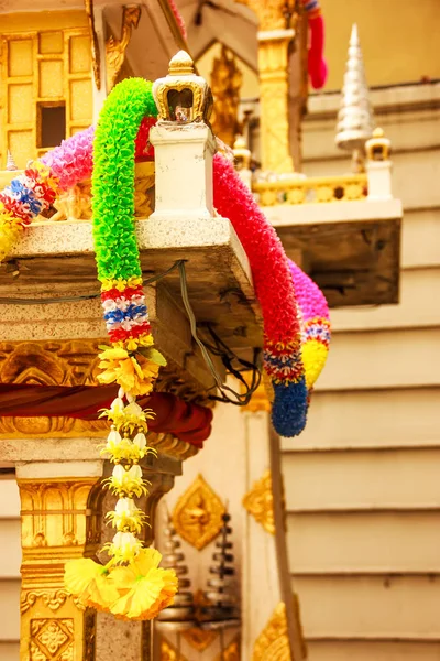 Colorful plastic flower garland on Traditional Thai outdoor spirit house shrine. — Stock Photo, Image