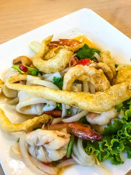 Ταϊλανδέζικη κουζίνα τροφίμων: Yum Sam Krob, τραγανό Maw ψάρια, βαθιά τηγανητό καλαμάρι και γαρίδες σε πικάντικη σαλάτα ανάμεικτη κάσιους σε λευκό πιάτο στο φόντο του τραπεζιού — Φωτογραφία Αρχείου