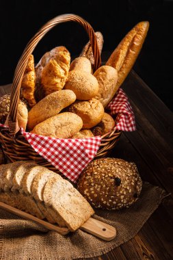 Koyu arka plan üzerinde ahşap masada ekmek ürün yelpazesine sahip. Natürmort ekmek doğal sabah ışık ile çeşitli..