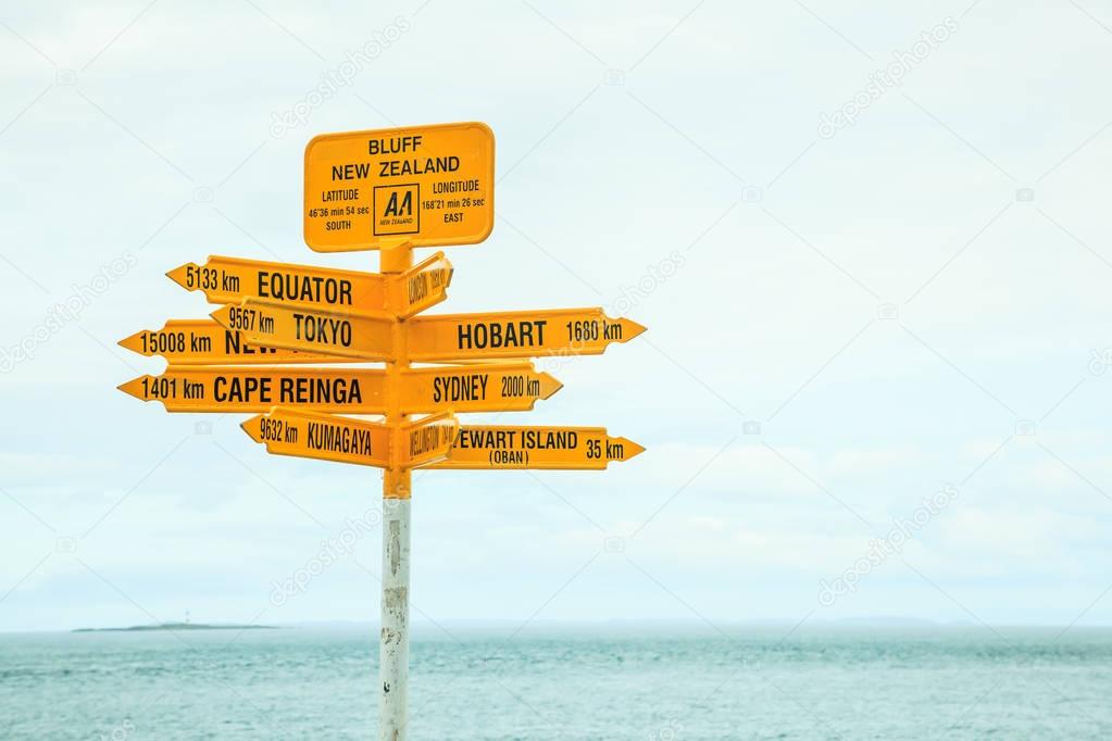 Bluff New Zealand yellow Signpost, with arrows pointing to different directions, major destinations, big cities such as Tokyo, Sydney, New York, Hobart, Kumagawa, Stewart Island, Cape Reinga, Equator