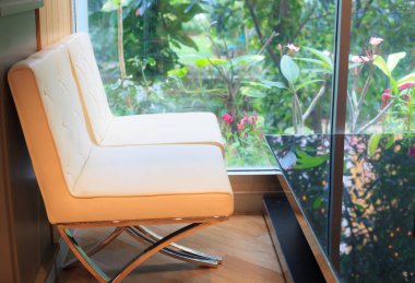 Rahatlatıcı an kahve Cafe, yumuşak krem deri koltuklar ile yeşil dekoratif Bahçe Manzaralı büyük pencere yanında siyah cam masa.