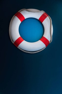 Bright Life Buoy in dark background. Personal life support flotation safety device for swimmers, passengers or marine personnel working in area exposed to water. Drowning Protection Equipment concept.