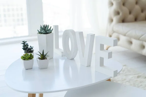 Любовний напис на білому столі з сукулентами в білій вітальні — стокове фото