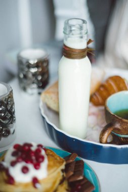 Yatakta, krep krema ve çilek, bir bardak çay, bir şişe süt ve bir baget bir tepsi ile Kahvaltı