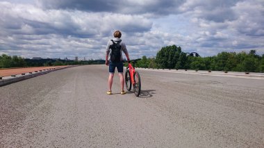 Bir adam bir sırt çantası ve terk edilmiş bir köprü bir bisiklet