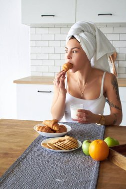 Kahvaltı yemek yerken bir akıllı telefon kullanan genç kadın