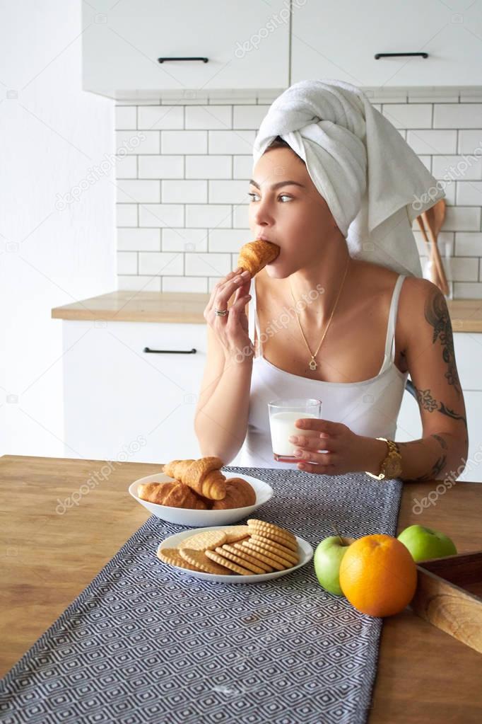 Young woman using a smartphone while eating breakfast