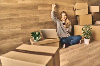 Mutlu kız yeni dairede bir bardak şarapla yerde oturuyor.