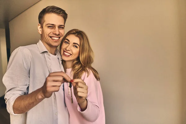 Happy young lovely couple showing key at their new apartment. — Stock Photo, Image