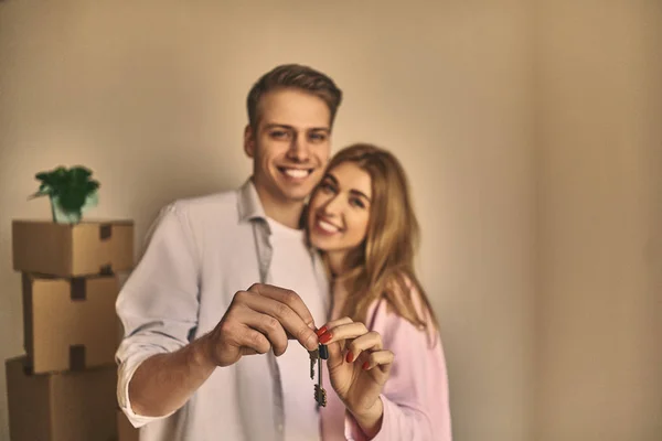 Feliz joven pareja encantadora mostrando la llave en su nuevo apartamento . —  Fotos de Stock