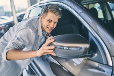 Man preparing to buy an automobile in showroom. Business concept
