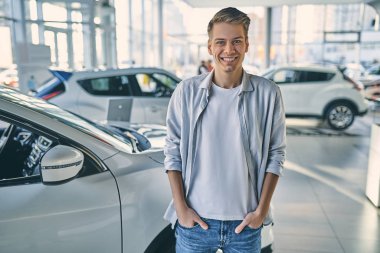 Happy man rejoicing buying a new car in showroom.