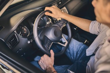 Male hand holding a steering wheel before purchasing a new autom