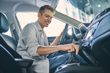 Stylish man sitting a new car and getting ready to drive.