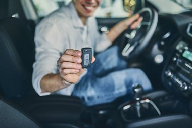 Male hand holding a steering wheel before purchasing a new autom