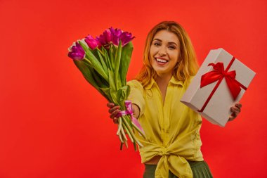 Mutlu bayan bir buket çiçekle ve hediye kutusuyla övünür.