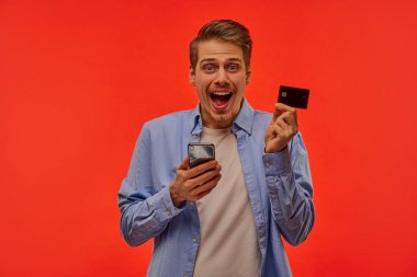 Elinde telefon ve kredi kartı olan heyecanlı bir adam..