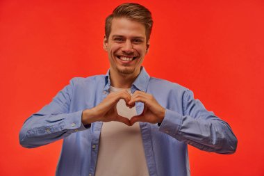 Mavi gömlekli mutlu adam bir kalp sembolü göster..
