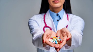 Siyah, uzun saçlı, kırmızı tırnaklı bir kadın tablet gösteriyor.