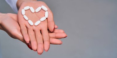 Kadın eli, aşkın sembolü olarak beyaz tabletleri tutar.