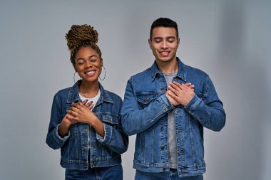 Gülümseyen erkek ve kadın gözleri kapalı ve elleri göğsünde minnetle hatırlıyorlar.