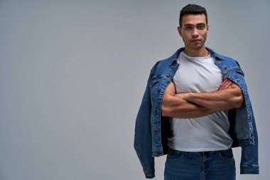 Atletik yapılı kıllı bir adam kameraya kendinden emin bir şekilde bakıyor..