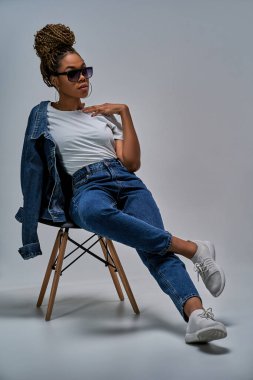 Küpeli kadın, omuz omuza kot ceketli örgü örüyor.