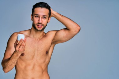 Krema kavanozlu, siyah saçlı, mutlu, bronzlaşmış bir adam.