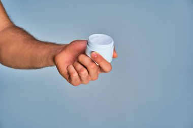 Elinde beyaz krema olan beyaz açık kavanoz.