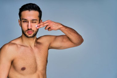 Yüzünde krema lekesi olan siyah saçlı ciddi bir adam kameraya bakıyor.