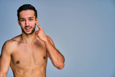 Yüzünde krema lekesi olan siyah saçlı mutlu adam kameraya bakar.