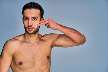 Siyah saçlı, yüzünde krem lekeleri olan, kameraya poz veren ciddi bir adam.