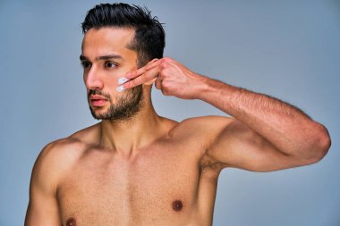 Yüzünde krem lekeleri olan siyah saçlı ciddi bir adam.