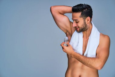 Elinde terleme önleyici olan beyaz banyo havlusu olan bir adam.