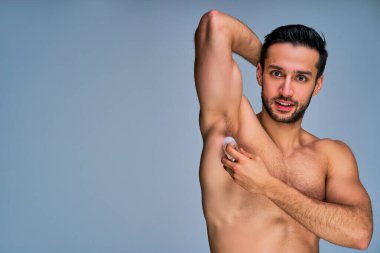 Gülümseyen, siyah saçlı, sakallı, terlemeyi önleyen bir adam.