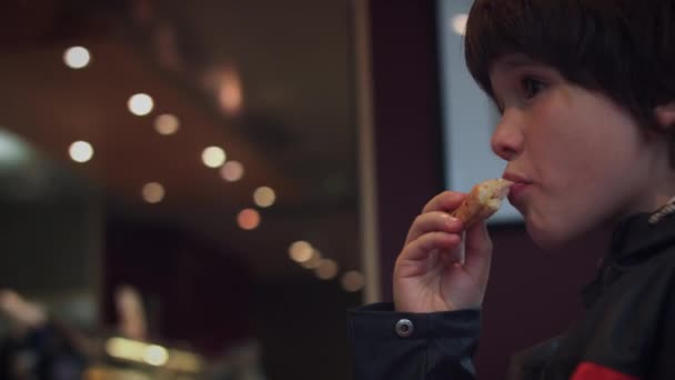 4K niño comiendo en un café y mirando las luces — Vídeo de stock