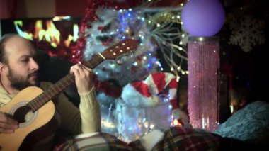 4 k Noel ve yeni yıl tatil adam şömineye gitar çalmak