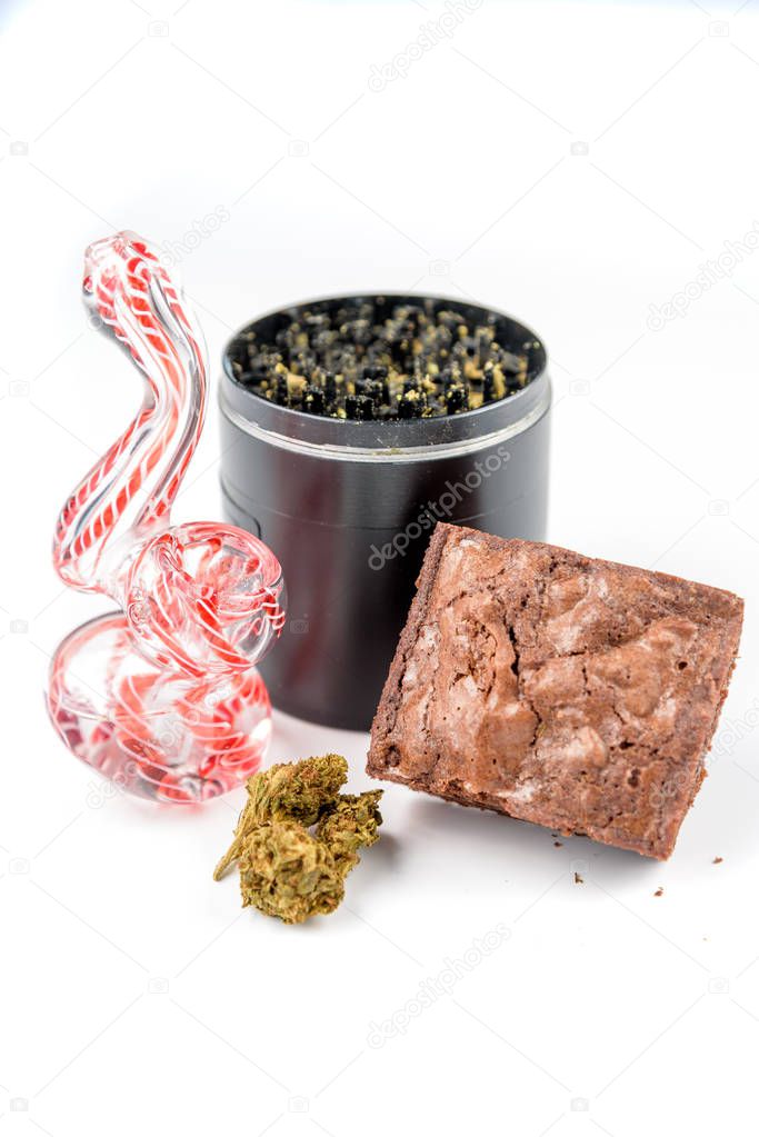 Close up of medical marijuana bud with a glass pipe, grinder, an