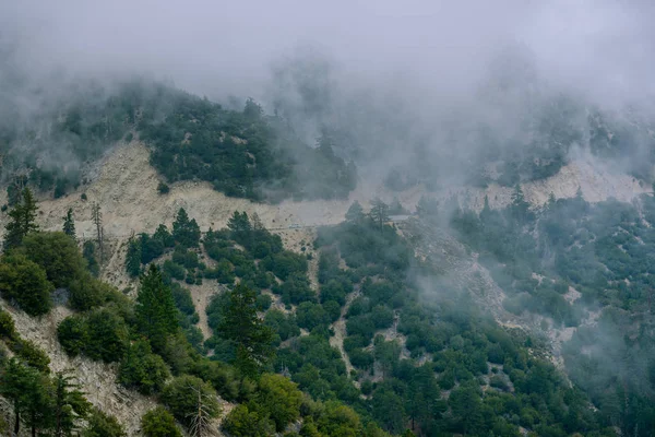 A highway passes through a mountain as a storm and heavy fog rolls in