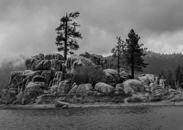 A mountain storm rolls in over a boulder island in the California Mountains. Black and White Edit