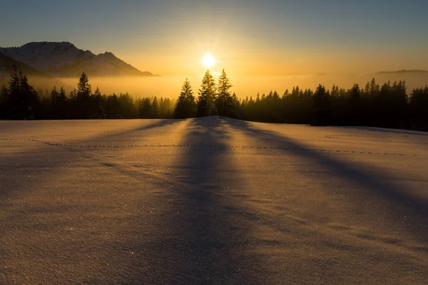 Magical sunset in a snowy mountain landscape. Sunbeams and backlighting. — Stock Photo, Image